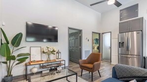 Una sala de estar moderna con un televisor de pantalla plana, una mesa de centro, un sofá y una silla.