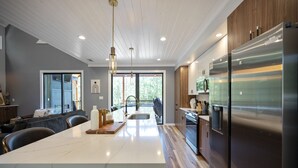 Een moderne keuken met een groot eiland, roestvrijstalen apparatuur en uitzicht op het groen.