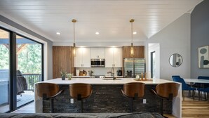 Een moderne keuken met een centraal eiland, houten kastjes en hanglampen.
