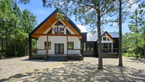 Een moderne chalet met een houten gevel, een overdekte veranda en een grindpad.