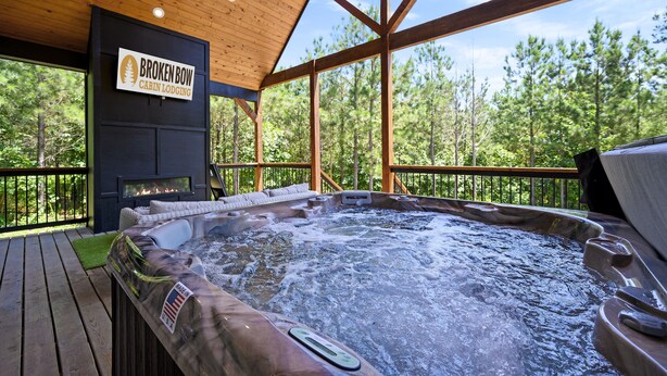 Een chalet met een hottub, een houten terras en een bord met de tekst 'Broken Bow Cabin Lodging'.