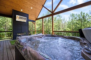Een chalet met een hottub, een houten terras en een bord met de tekst 'Broken Bow Cabin Lodging'.