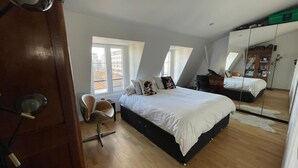Quarto com cama, cadeira, escrivaninha e guarda-roupa.