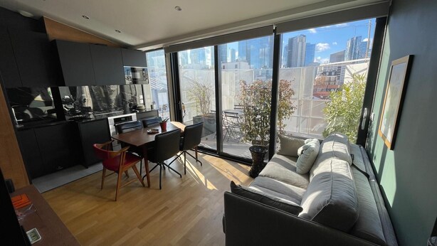 Um apartamento moderno com área de refeições, cozinha e um sofá com vista para a cidade.