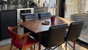 Uma cozinha moderna com armários escuros, uma mesa de jantar de madeira e cadeiras pretas.