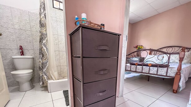 A bathroom with a toilet, a cabinet, and a bed with a metal frame. - Ramona's place - Serenity in your eyes. (San Juan)