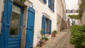A narrow cobblestone street with buildings featuring blue shutters and potted plants. - Lovely 2* house - Auray port de St Goustan (Auray)