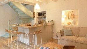 A modern kitchen with a central island, bar stools, a staircase, and a living area with a sofa and a lamp. - Lovely 2* house - Auray port de St Goustan (Auray)