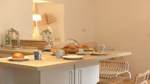 A breakfast setup with a basket of croissants, a coffee cup, and a plate of food on a wooden table. - Lovely 2* house - Auray port de St Goustan (Auray)