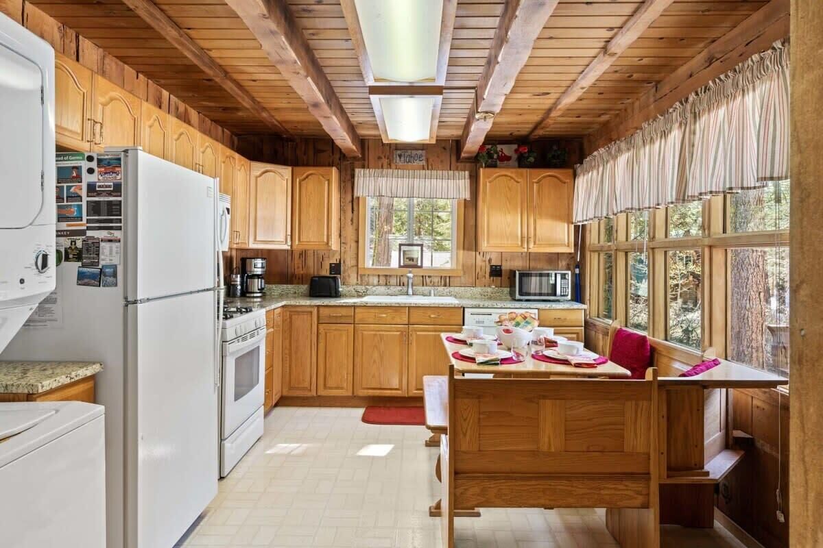 Une cuisine rustique aménagée dans une cabane en bois, comprenant un réfrigérateur, une cuisinière, un four à micro-ondes et des placards en bois.
