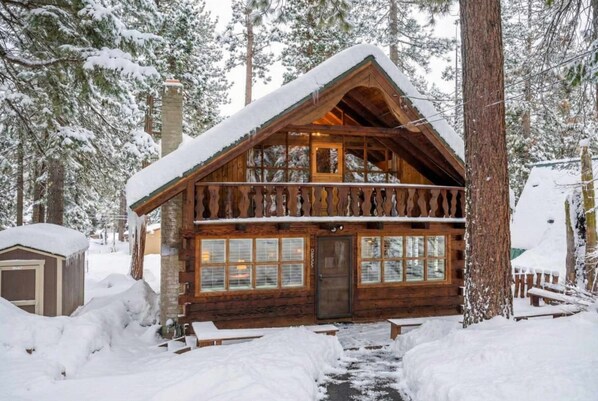 A log cabin with a wooden exterior, large windows, and a chimney.