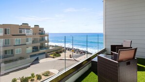Ein Balkon mit Blick auf das Meer, eine Rasenfläche und ein Gebäude mit vielen Fenstern.