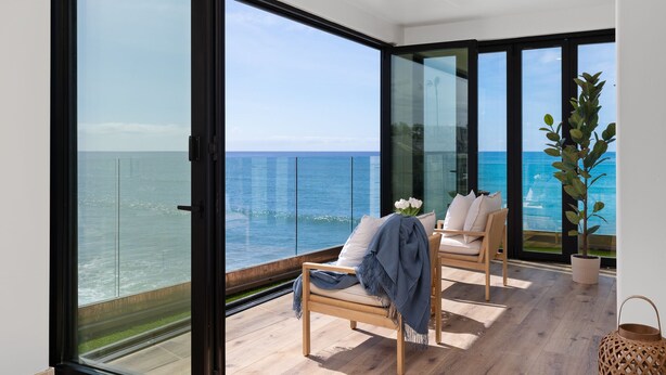 Ein Balkon mit Meerblick, ein Sessel mit Decke und ein Topfpflanze.