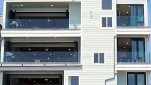 Ein modernes, mehrgeschossiges Gebäude mit Balkonen, großen Fenstern und einer weißen Fassade.