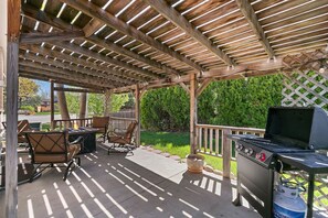 An outdoor patio with a grill, chairs, and a fire pit.