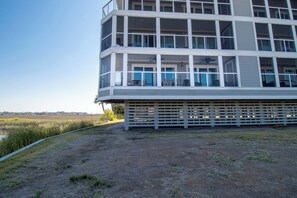 A multi-story building with balconies, a covered outdoor area, and a view of the water.