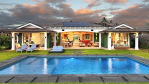 Une maison à deux étages dotée d’une piscine, d’un espace extérieur aménagé et de panneaux solaires sur le toit.
