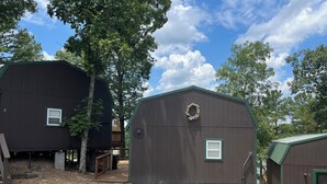 Ein rustikales Blockhaus mit grüner Dachdeckung, einer kleinen Veranda und einem Schotterweg.