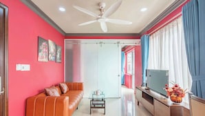 A living room with a sofa, a coffee table, a TV, and a ceiling fan. - La Serena Hotel & Apartment (Ho Chi Minh City)