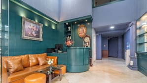 A modern lobby with teal walls, a leather sofa, and a reception desk. - La Serena Hotel & Apartment (Ho Chi Minh City)