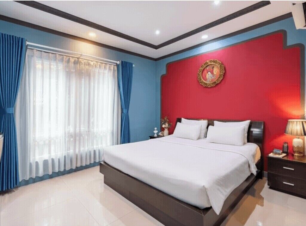 Un dormitorio moderno con una cama grande, una pared de acento roja y un marco circular decorativo.