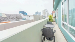 A balcony with a table and chairs, a potted plant, and a view of the cityscape. - La Serena Hotel & Apartment (Ho Chi Minh City)