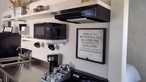 A kitchen with a microwave, coffee maker, and a framed quote on the wall.
