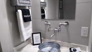 A bathroom with a sink, a mirror, and a towel rack with a towel labeled "MAKEUP".