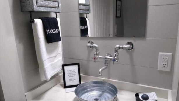 A bathroom with a sink, a mirror, and a towel rack with a towel labeled "MAKEUP". - Country Dome Suites (Bellville)