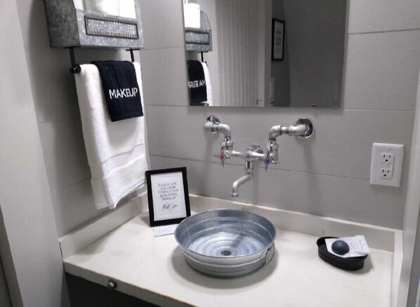 A bathroom with a sink, a mirror, and a towel rack with a towel labeled "MAKEUP". - Country Dome Suites (Bellville)