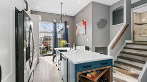 Une cuisine moderne dotée d’un grand îlot central, d’un meuble-bar intégré et donnant sur le jardin.