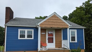 A two-story house with a front porch, a mailbox, and a number sign. - Little Blue Farmhouse (Jonesville)