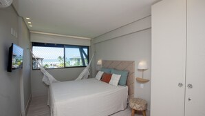 Una camera da letto con un letto, lampade da comodino, un comodino e vista sull'oceano attraverso una finestra.