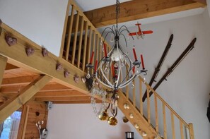 Een houten trap met een kroonluchter en ski-uitrusting aan de muur.
