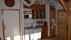 A kitchen with wooden cabinets, a microwave, a sink, and a refrigerator. - Appartement Plein Sud (Les Deux Alpes)