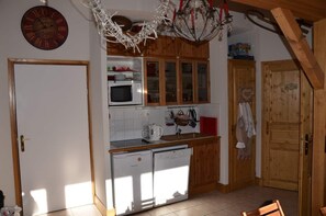 Een keuken met houten kastjes, een magnetron, een spoelbak en een koelkast.