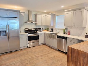 Une cuisine moderne dotée d’appareils électroménagers en acier inoxydable, de meubles blancs et d’un dosseret de carrelage disposé en motif chevron.