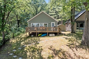A cabin with a deck, surrounded by trees.