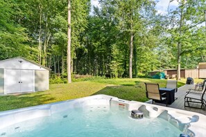 Relax in the hot tub surrounded by lush greenery and trees.