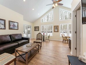 Relax in this cozy living space with a high ceiling, ceiling fan, and large window offering a view of the surrounding landscape.
