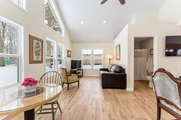 Relax in this inviting living space with a glass dining table, comfortable sofa, and large windows.