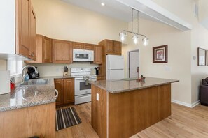 Enjoy cooking in this well-lit kitchen with a central island, microwave, oven, and refrigerator.