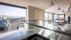 A modern interior with a glass balcony overlooking a village. - Quarry House -  An architecturally inspiring house with sea views (West Charleton)