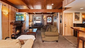 Ein gemütliches Blockhaus-Interieur mit Kamin, Holzwänden, einer Couch und einem Fernseher.