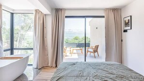 Un dormitorio con una cama grande, una bañera y un balcón con una mesa y sillas.
