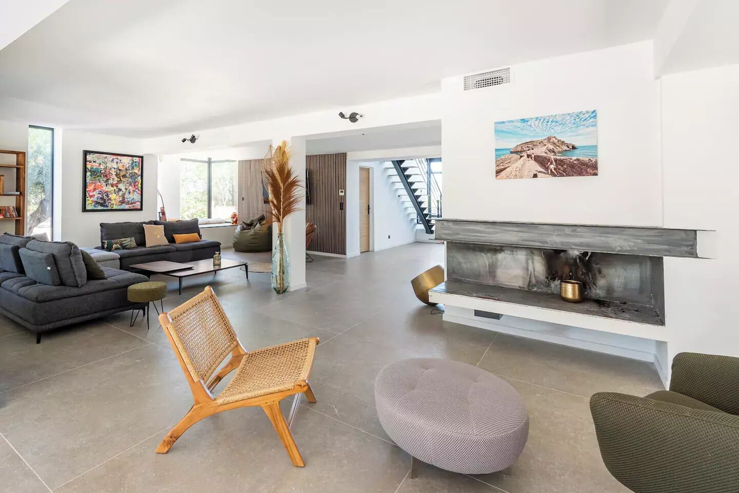 Un salon spacieux doté d’une cheminée, de meubles modernes et de grandes fenêtres.
