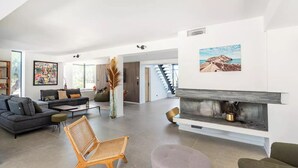 Amplia sala de estar con chimenea, muebles modernos y ventanas grandes.