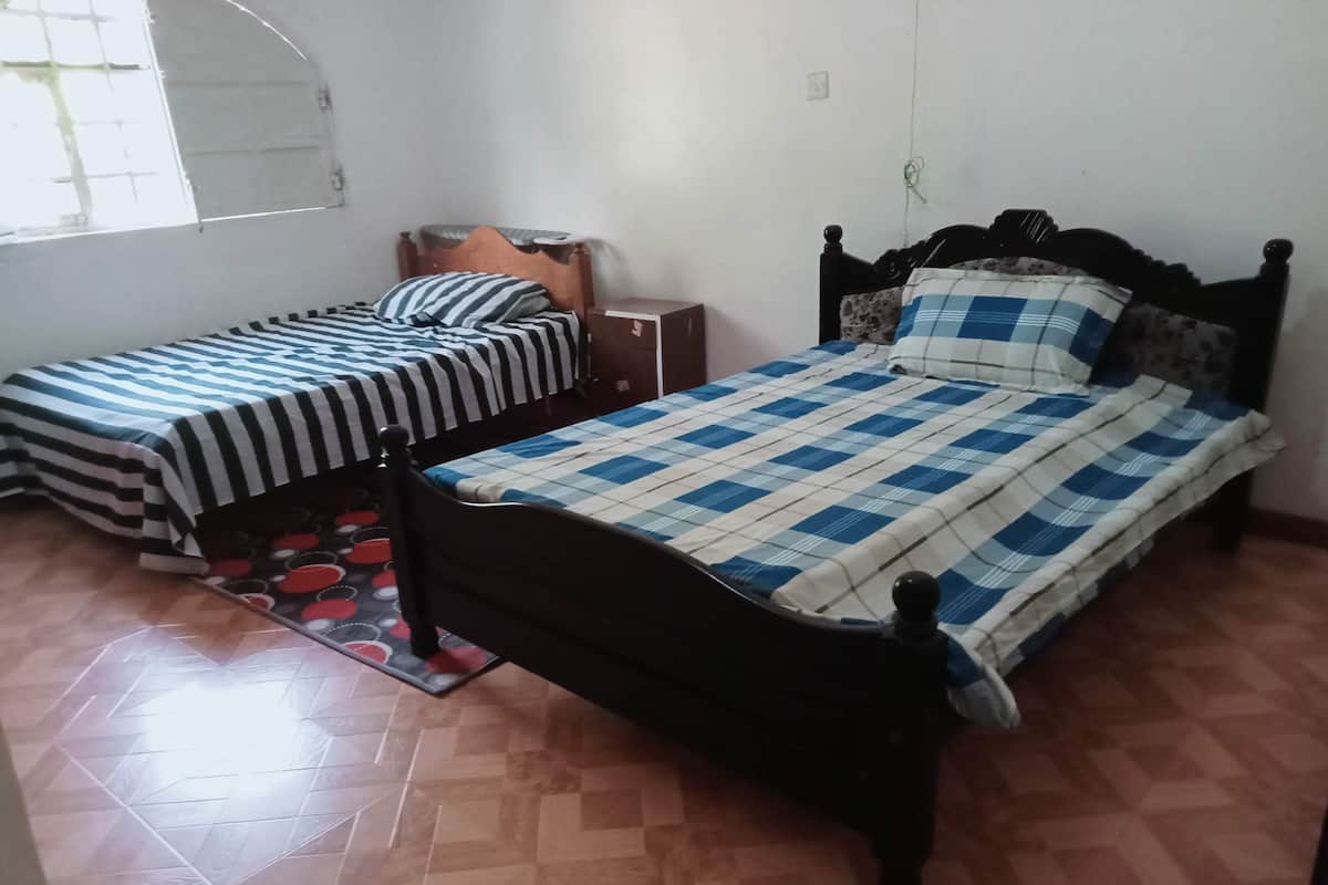 Ein Schlafzimmer mit zwei Einzelbetten, Holzboden und einem kleinen Nachttisch.