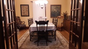 A dining area with a table set for four, surrounded by chairs, a chandelier, and artwork on the walls. - Terrapin Hostel (Kingfield)