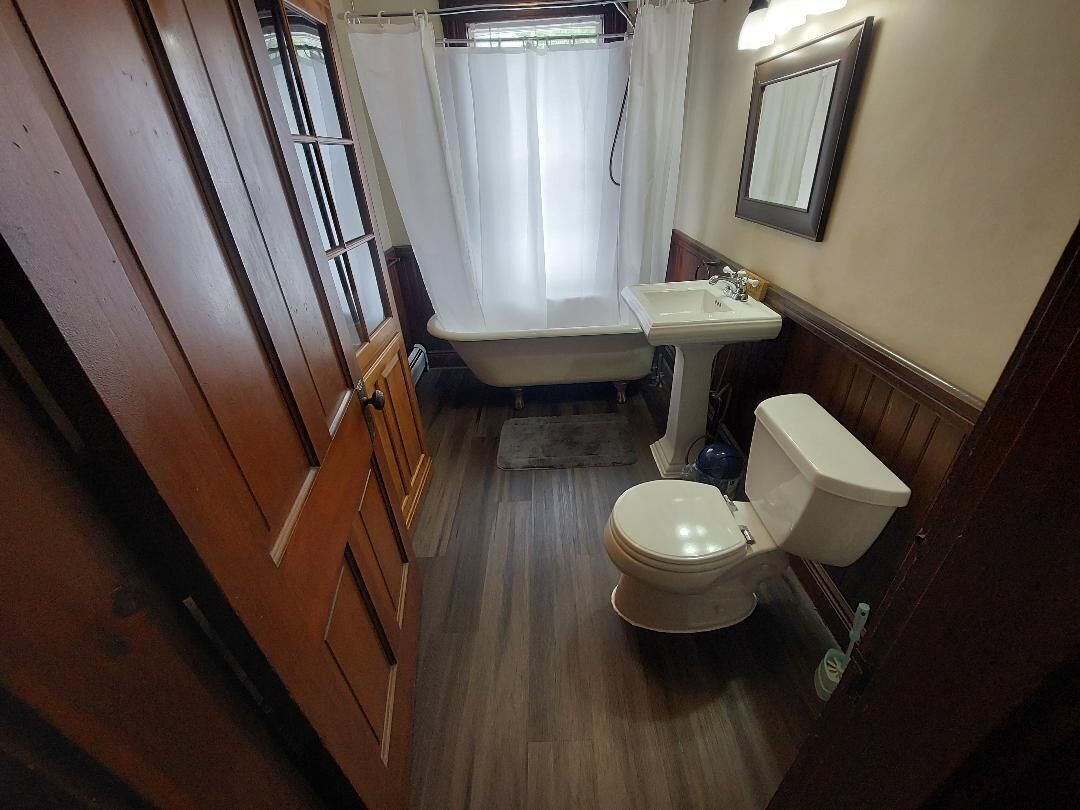 A bathroom with a bathtub, toilet, sink, and wooden cabinets.